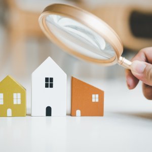 Magnifying glass and house model, house selection, real estate concept.